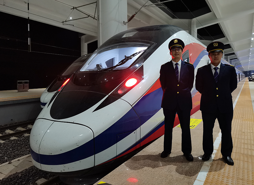 劉銀能（右一）與中國師父鄔俊鴻在動車組前合影。受訪者供圖